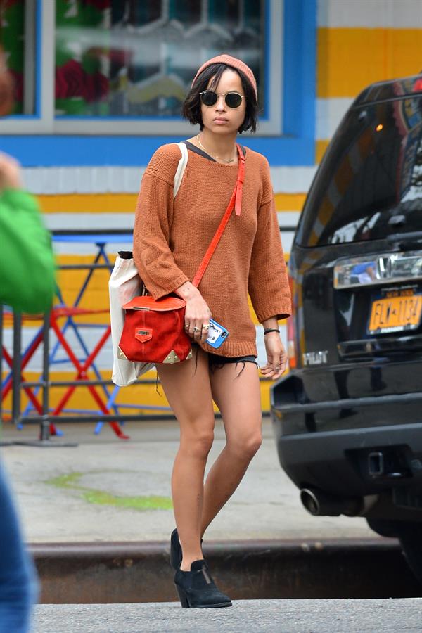 Zoe Kravitz walking in shorts and an orange top