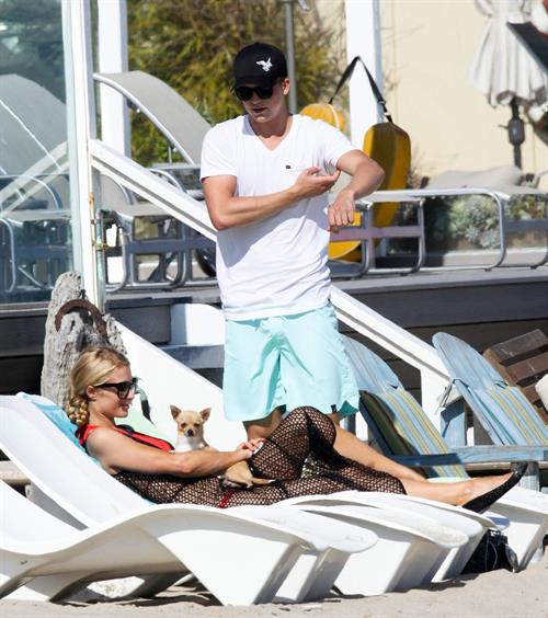 Paris Hilton at the beach in a skimpy red bikini and fishnet kaftan in Malibu.July 12, 2013