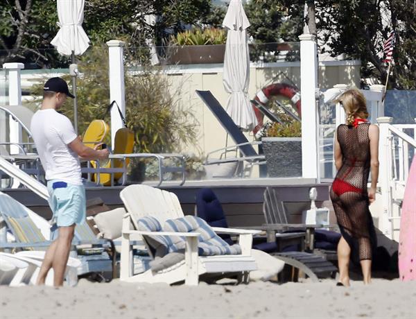 Paris Hilton at the beach in a skimpy red bikini and fishnet kaftan in Malibu.July 12, 2013