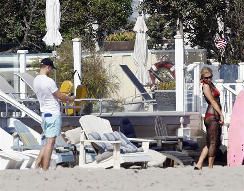 Paris Hilton at the beach in a skimpy red bikini and fishnet kaftan in Malibu.July 12, 2013