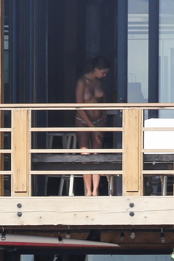 Cara Delevingne topless on a balcony