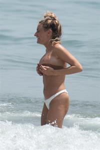 Amber Davies sexy boobs bouncing around in a loose bikini at the beach seen by paparazzi.

