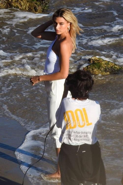 Hailey Bieber Pictures Hailey Bieber braless nipples pokies in a white top at the beach seen by paparazzi during a photo shoot.