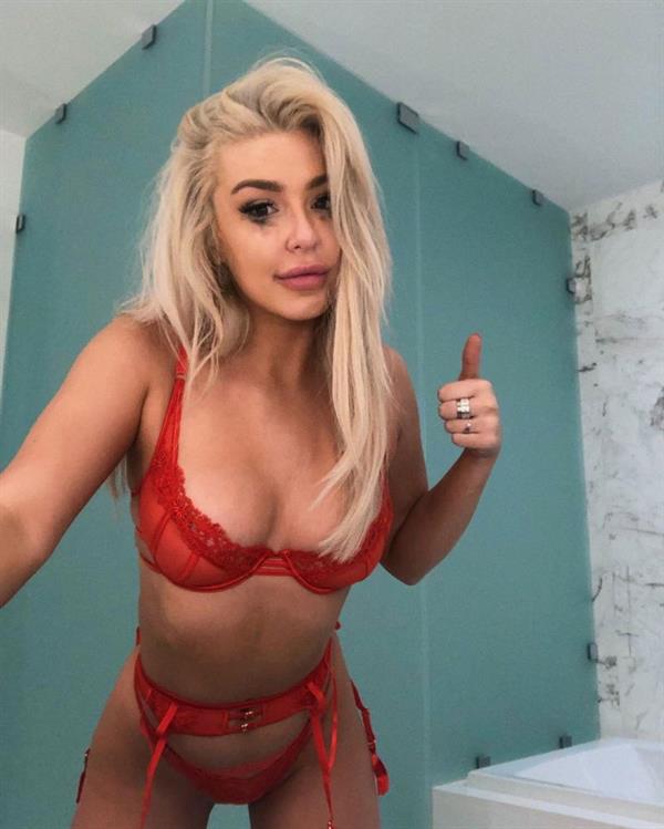 Tana Mongeau in sexy red lingerie showing off her big boobs cleavage in a bra and thong panties.