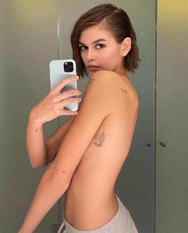 Kaia Gerber topless and sexy new selfie covering her nude boobs showing off her tattoos.