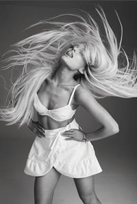 Ariana Grande sexy in just a white bra top and white skirt showing nice cleavage and her long blonde hair.