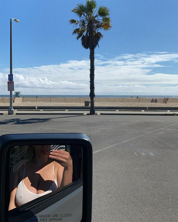 Lindsey Pelas braless boobs showing off her big tits pokies and cleavage in a slightly see through white tank top in the mirror of her car.