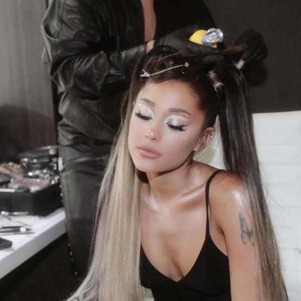 Ariana Grande braless boobs showing nice cleavage with her tits in a sexy little black top bent forward while getting her hair done.