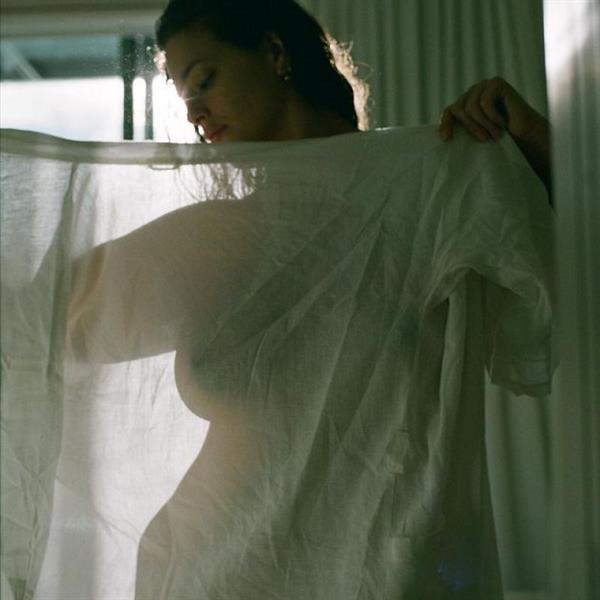 Ashley Graham nude boobs on display behind a see through shirt she is holding up showing off her naked big tits.