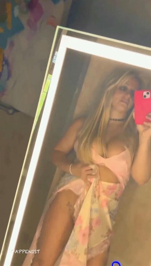 Britney Spears huge boobs showing nice cleavage with her big tits taking a selfie while at the same time pulling up her skirt pantyless nearly showing her pussy.